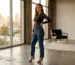 Woman wearing black lace bodysuit with high-waisted jeans and strappy heels in modern loft apartment