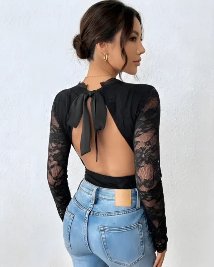 Back view of a black lace backless bodysuit paired with blue jeans and an open-back bow