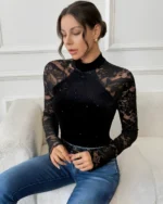 Seated front view of a black long sleeve lace bodysuit paired with blue jeans