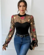 Front view of a black embroidered rose lace bodysuit styled with blue jeans