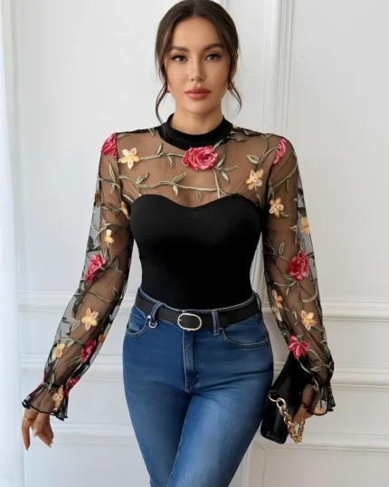 Front view of a black embroidered rose lace bodysuit styled with blue jeans