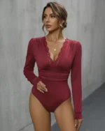 Front view of a model wearing a red long sleeve lace bodysuit with a V-neck and ruched waist
