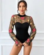 Front view of a model wearing a black embroidered rose lace bodysuit with sheer mesh long sleeves