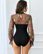 Back view of a black floral embroidered lace bodysuit with long sheer mesh sleeves