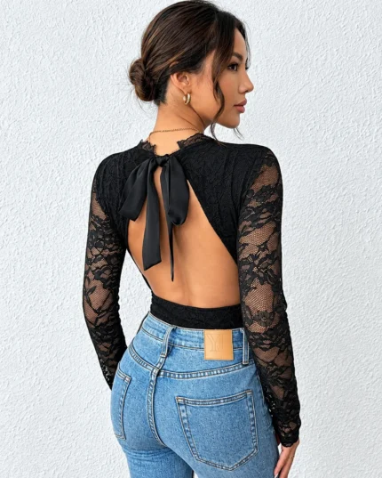 Back view of a black lace backless bodysuit paired with blue jeans and an open-back bow