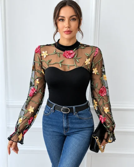 Front view of a black embroidered rose lace bodysuit styled with blue jeans